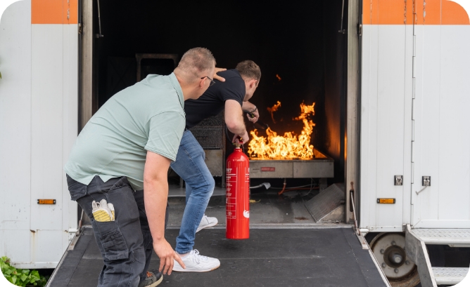 Cursist en instructeur blussen brand tijdens BHV training